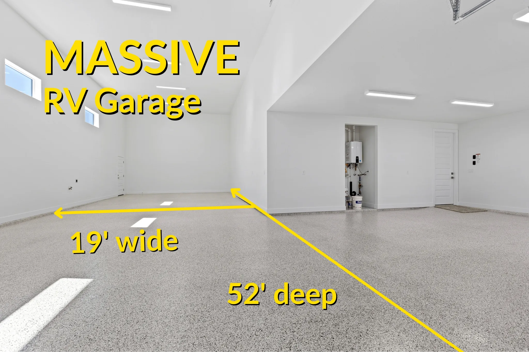 Spacious garage featuring a durable speckled epoxy floor, multiple linear ceiling lights, high ceilings, and a built-in water heater system