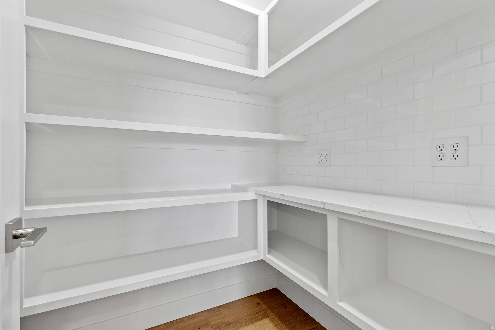 Pantry with white shelving, a white subway tile backsplash, and a white countertop