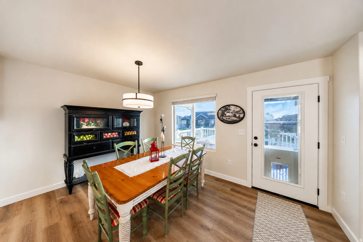 Dining area featuring wood-finish flooring, a contemporary pendant light fixture, and a glass-paneled door opening to an exterior deck