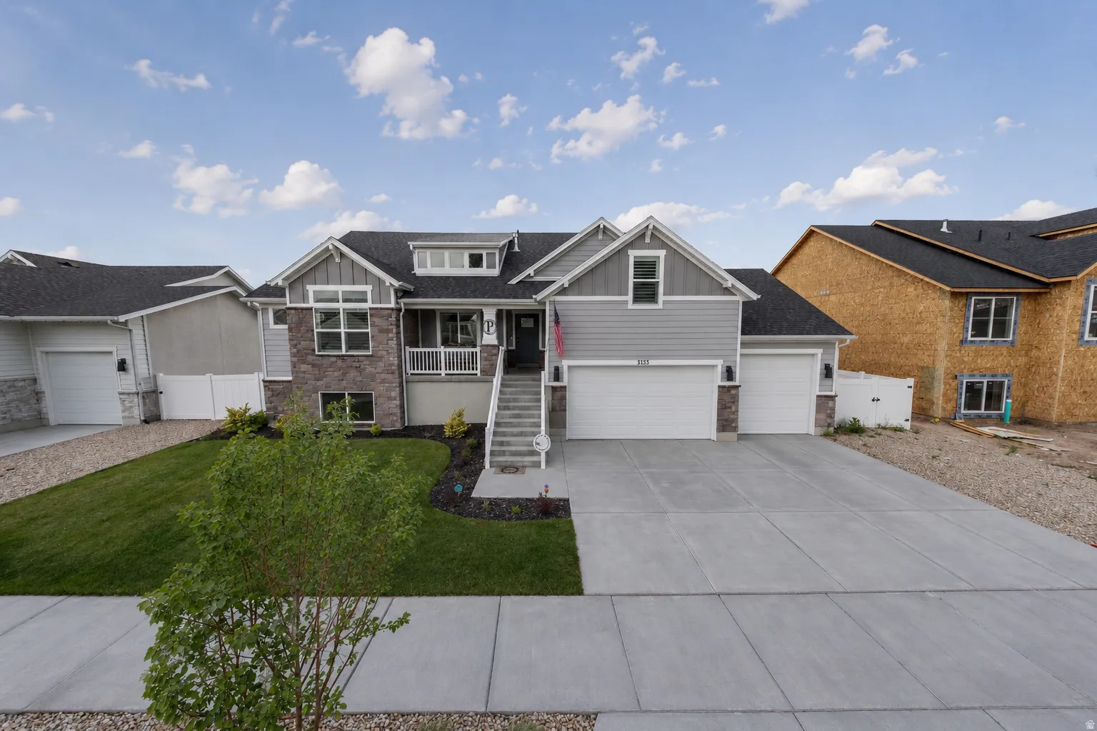 Modern Craftsman-style exterior featuring a multi-gabled roofline, stone accents, and gray cement board siding