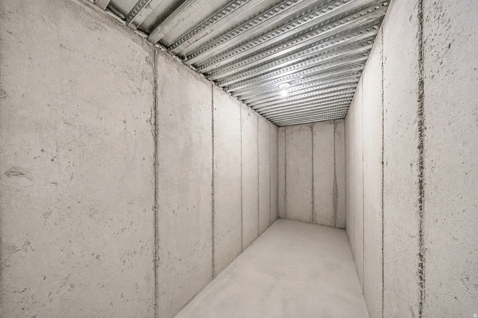 Cold storage in the unfinished basement area featuring concrete walls and flooring