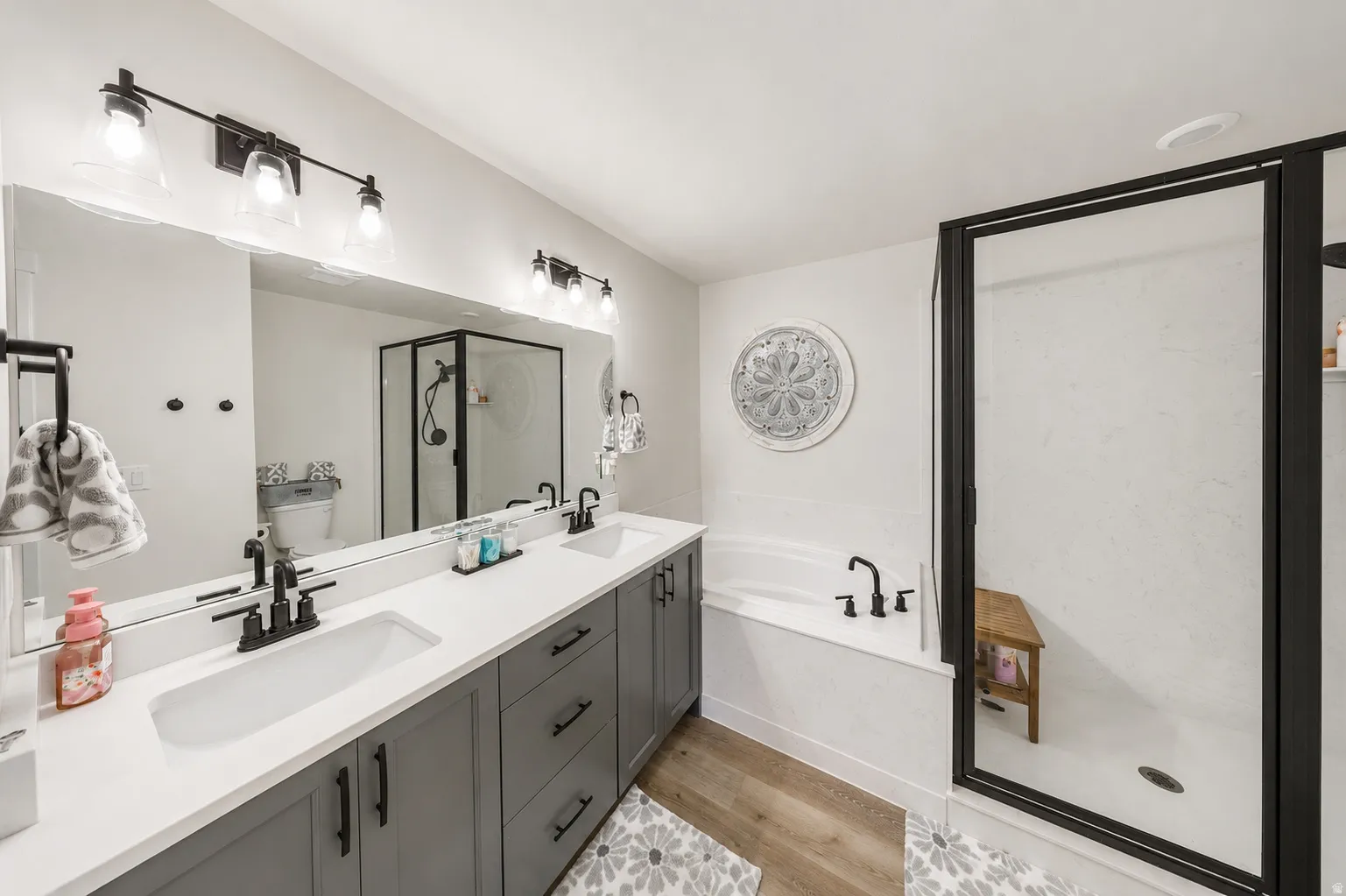 Primary bathroom featuring a double vanity with matte black fixtures, integrated sinks, a white quartz countertop, and gray cabinetry