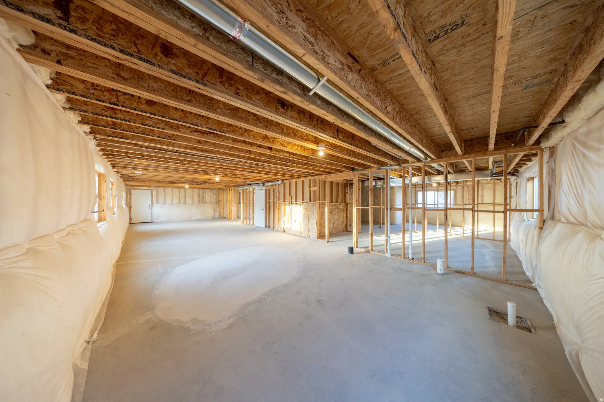 Unfinished basement featuring exposed wood joists, framed walls, pre-plumbed and concrete flooring