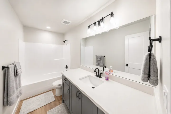 Main level bathroom featuring a single vanity with quartz countertop, undermount sink, and gray cabinetry