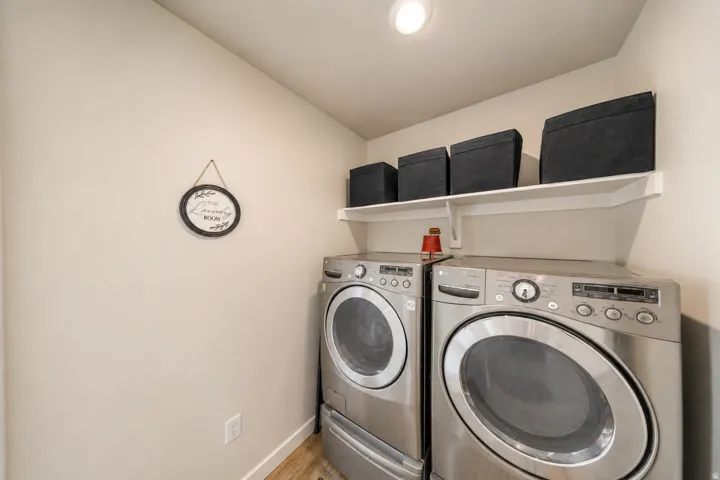Dedicated laundry area featuring overhead shelving, recessed lighting, and wood-finish flooring