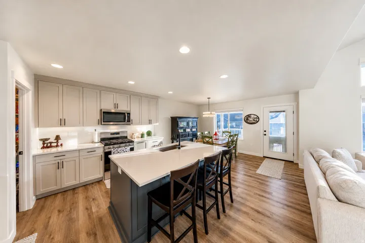 Open-concept kitchen featuring light-toned cabinetry, stainless steel appliances, and a central island with countertop seating and additional storage