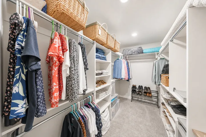Walk-in closet featuring built-in shelving, multiple hanging rods, recessed lighting, and carpet flooring