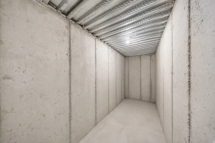 Cold storage in the unfinished basement area featuring concrete walls and flooring