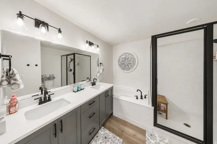 Primary bathroom featuring a double vanity with matte black fixtures, integrated sinks, a white quartz countertop, and gray cabinetry