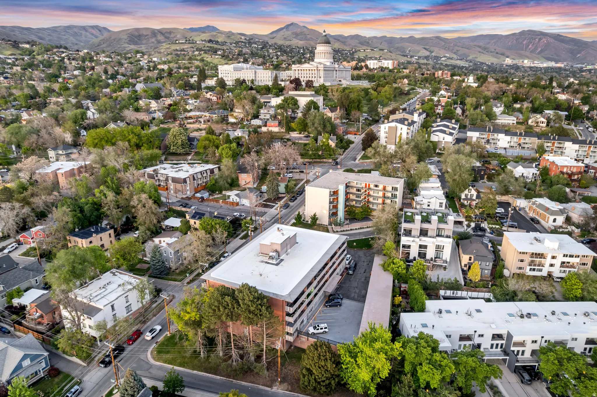 Aerial perspective showcasing a dense urban neighborhood featuring a mix of residential structures, commercial buildings, and mature trees