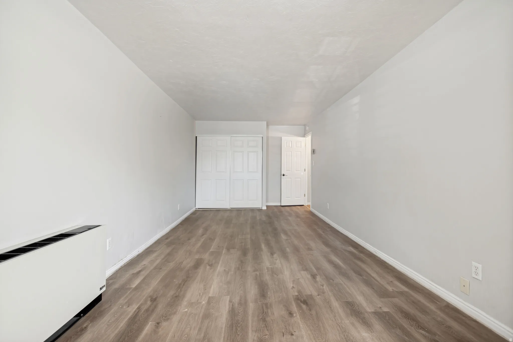 Expansive room featuring wood-finish flooring, light grey walls, and white trim