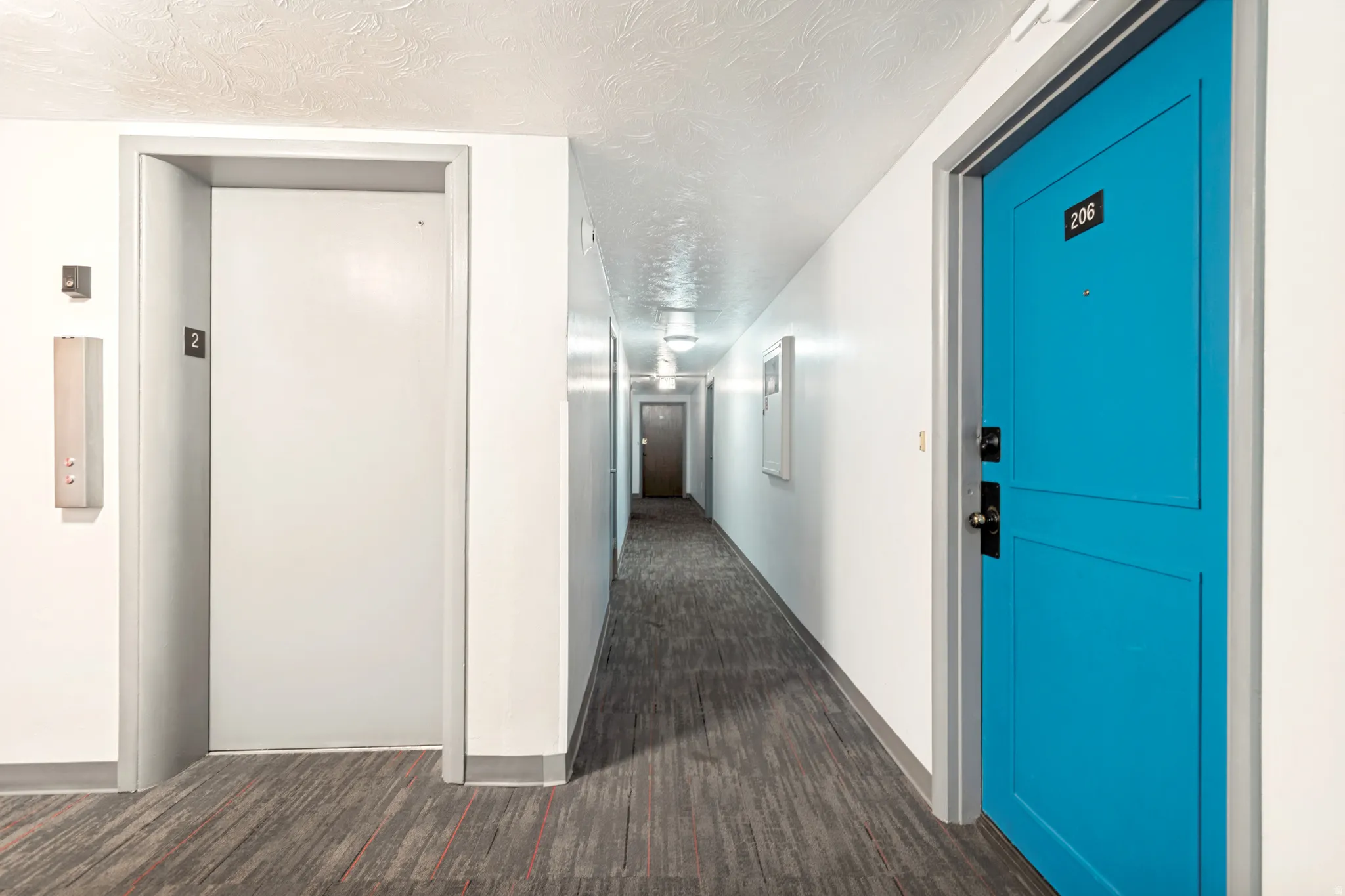 Modern entryway featuring a bright blue panel door, dark hardware, and a number plaque