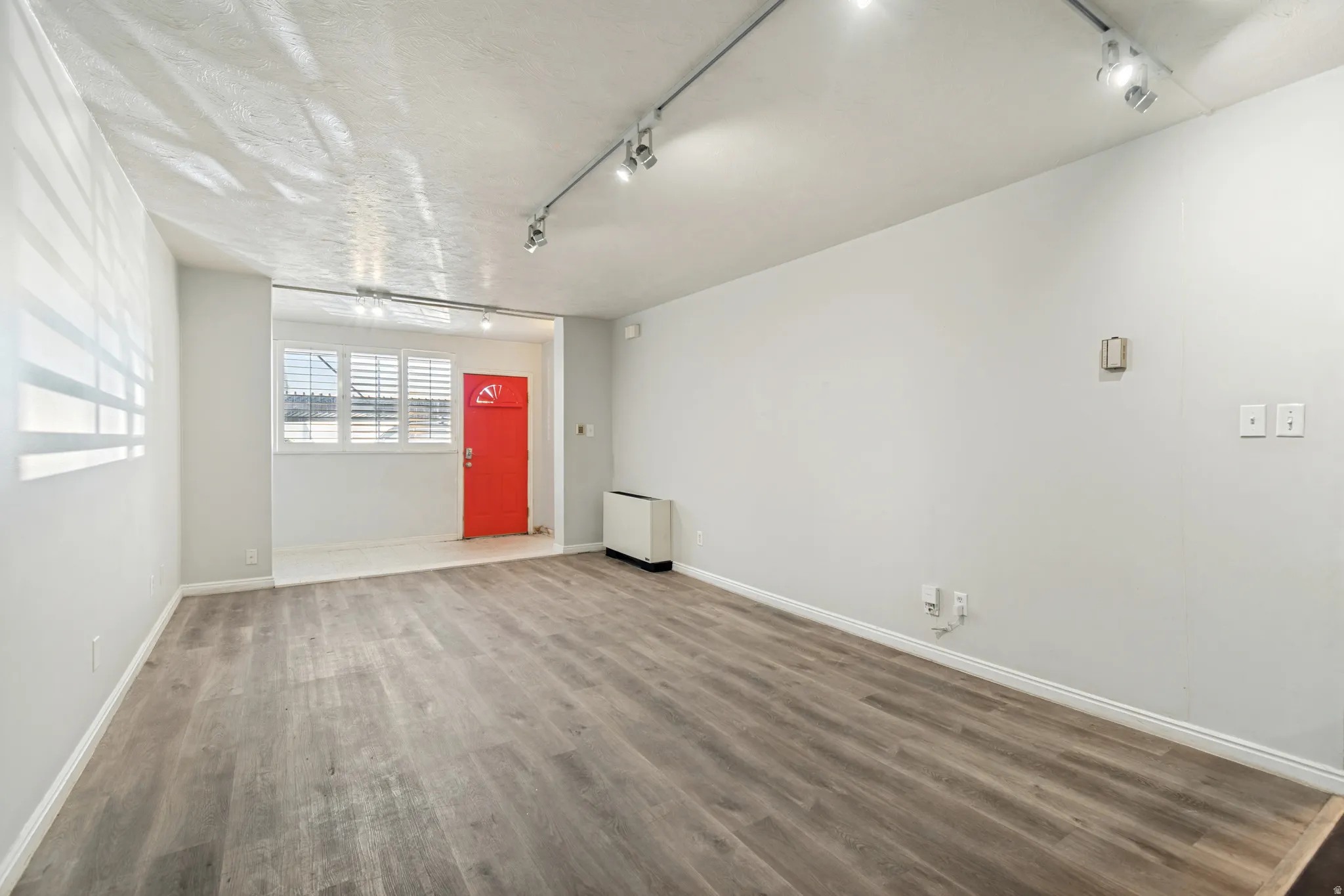 Open concept living area featuring wood-finish flooring, recessed entry, and a vibrant red entry door