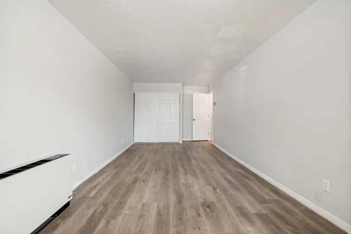 Expansive room featuring wood-finish flooring, light grey walls, and white trim