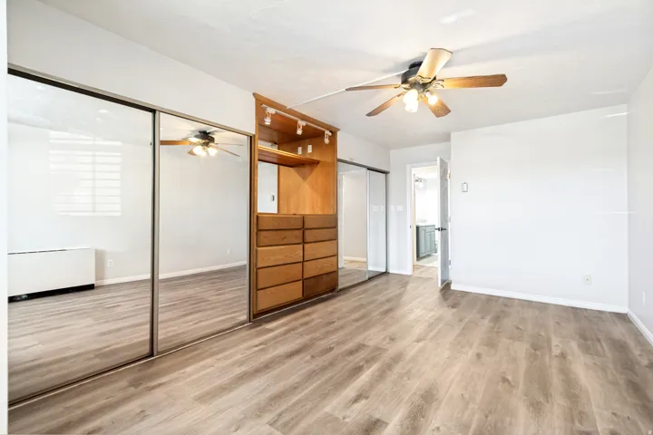 Spacious interior featuring wood-finish flooring, a built-in wood-tone storage unit with drawers and shelving, and track lighting