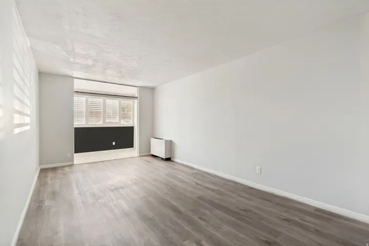 Spacious room featuring wood-finish flooring, white baseboards, and neutral wall paint