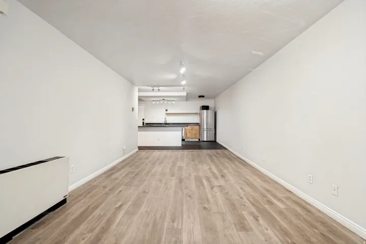 Spacious main living area featuring wood-finish flooring, white baseboards, and neutral wall tones