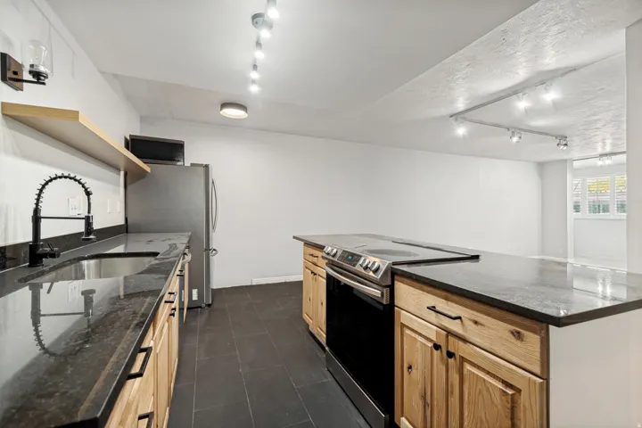 Functional kitchen featuring dark stone countertops, wood-finish cabinetry, and stainless steel appliances