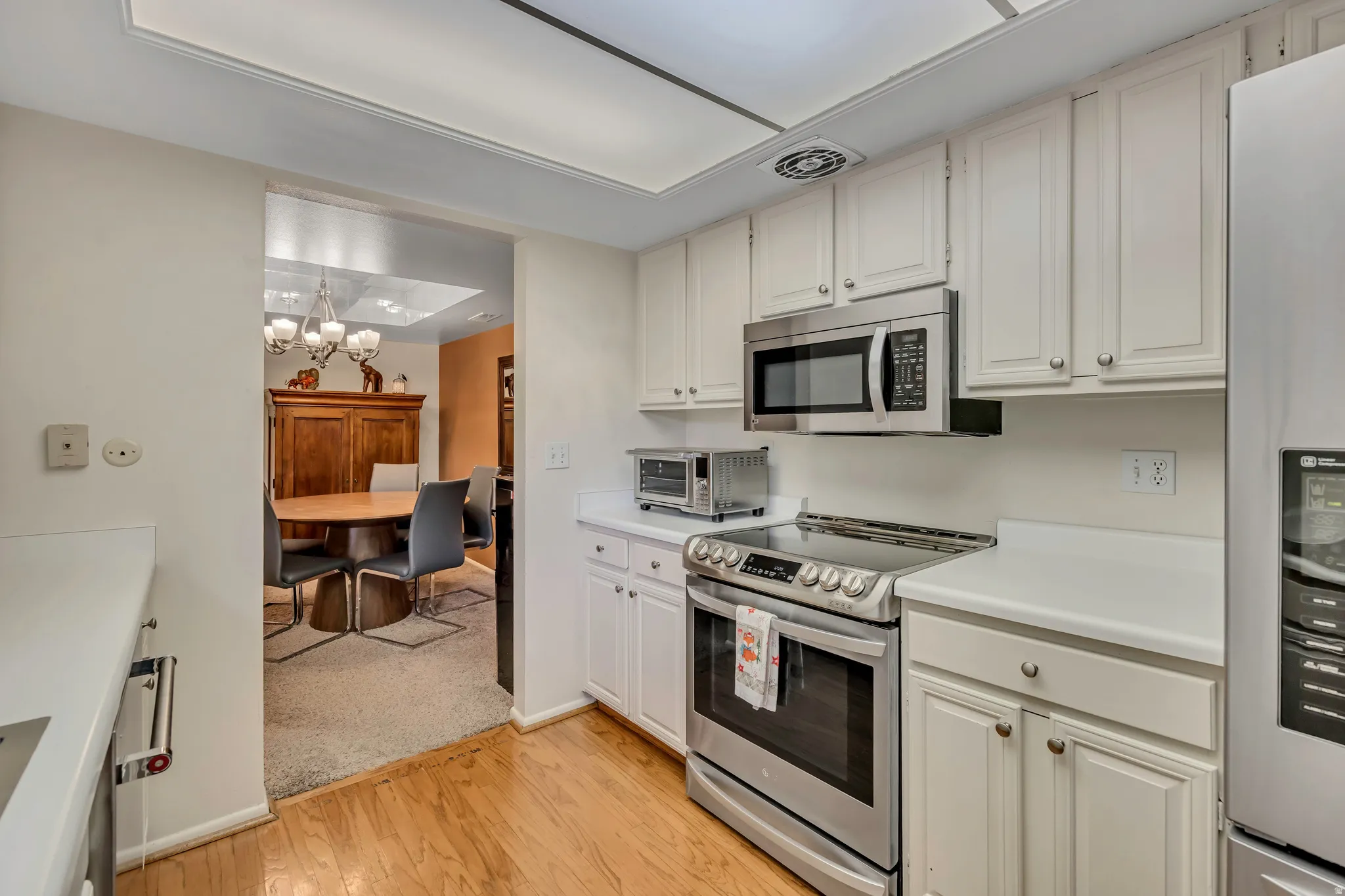 Kitchen featuring white cabinetry, white countertops, a stainless steel sink with a gooseneck faucet, a stainless steel appliances, and hard wood flooring