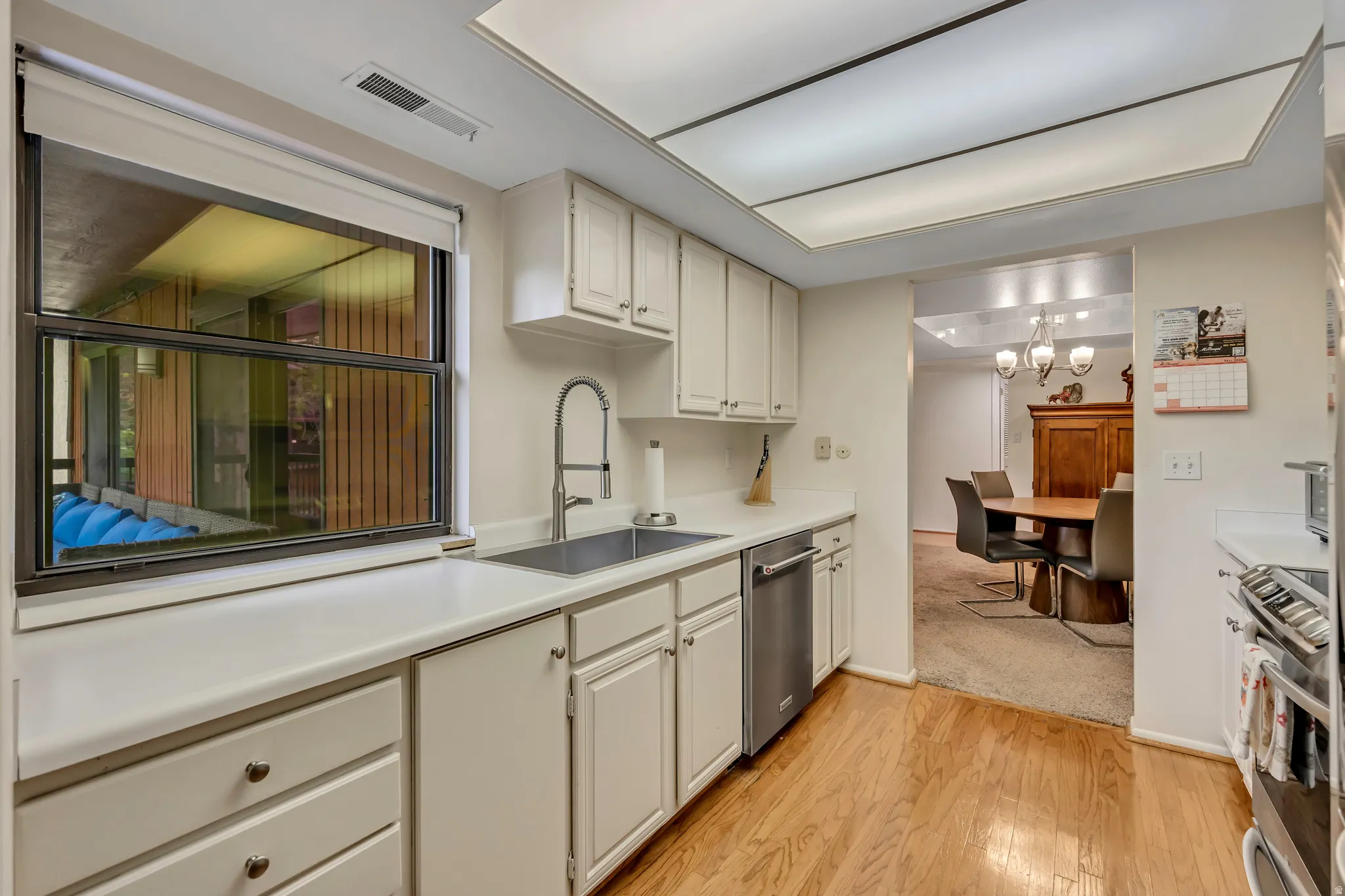 Kitchen featuring white cabinetry, white countertops, a stainless steel sink with a gooseneck faucet, a stainless steel appliances, and hard wood flooring