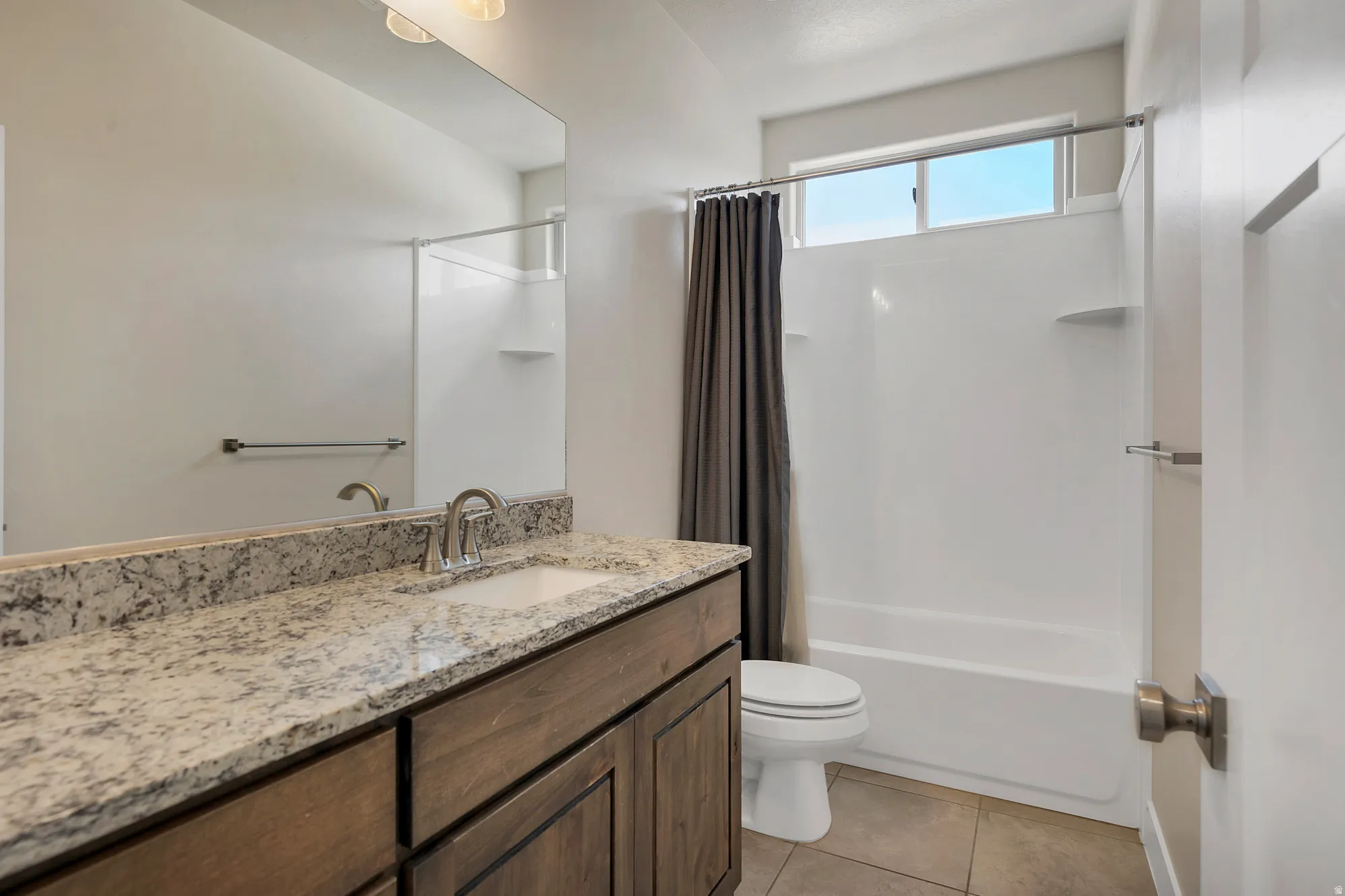 Bathroom featuring a wood-finish vanity with a granite-style countertop, undermount sink, and brushed nickel faucet