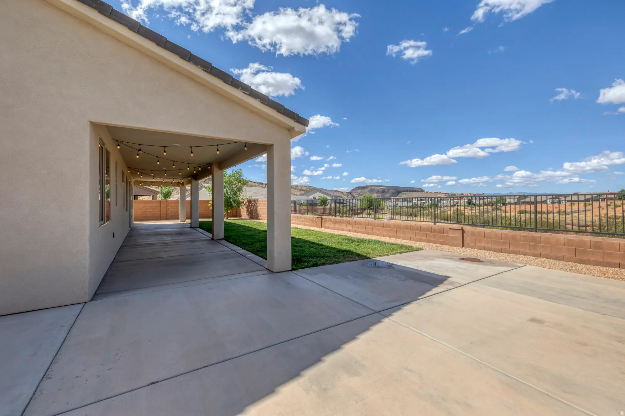 Expansive covered patio featuring string lighting, stucco exterior, and a concrete surface