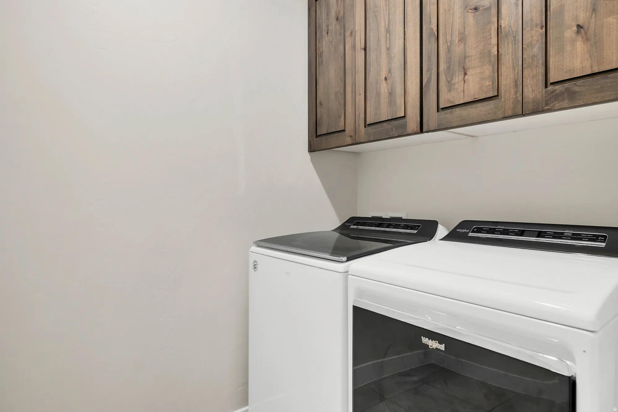 Laundry area featuring dark wood-finish cabinetry and light-colored walls