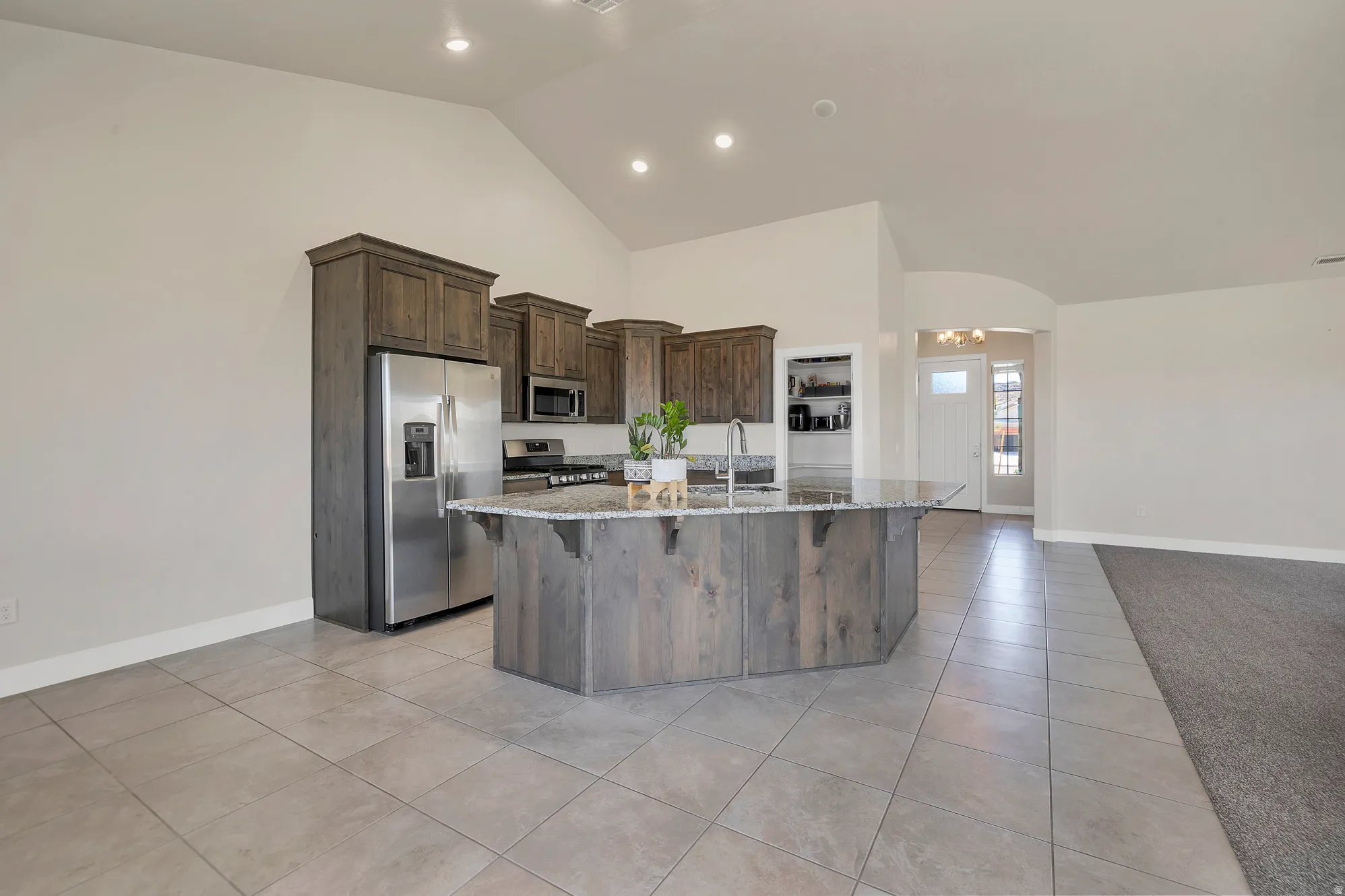 Spacious kitchen featuring an island with a breakfast bar, stainless steel appliances, wood-finish cabinetry, and recessed lighting