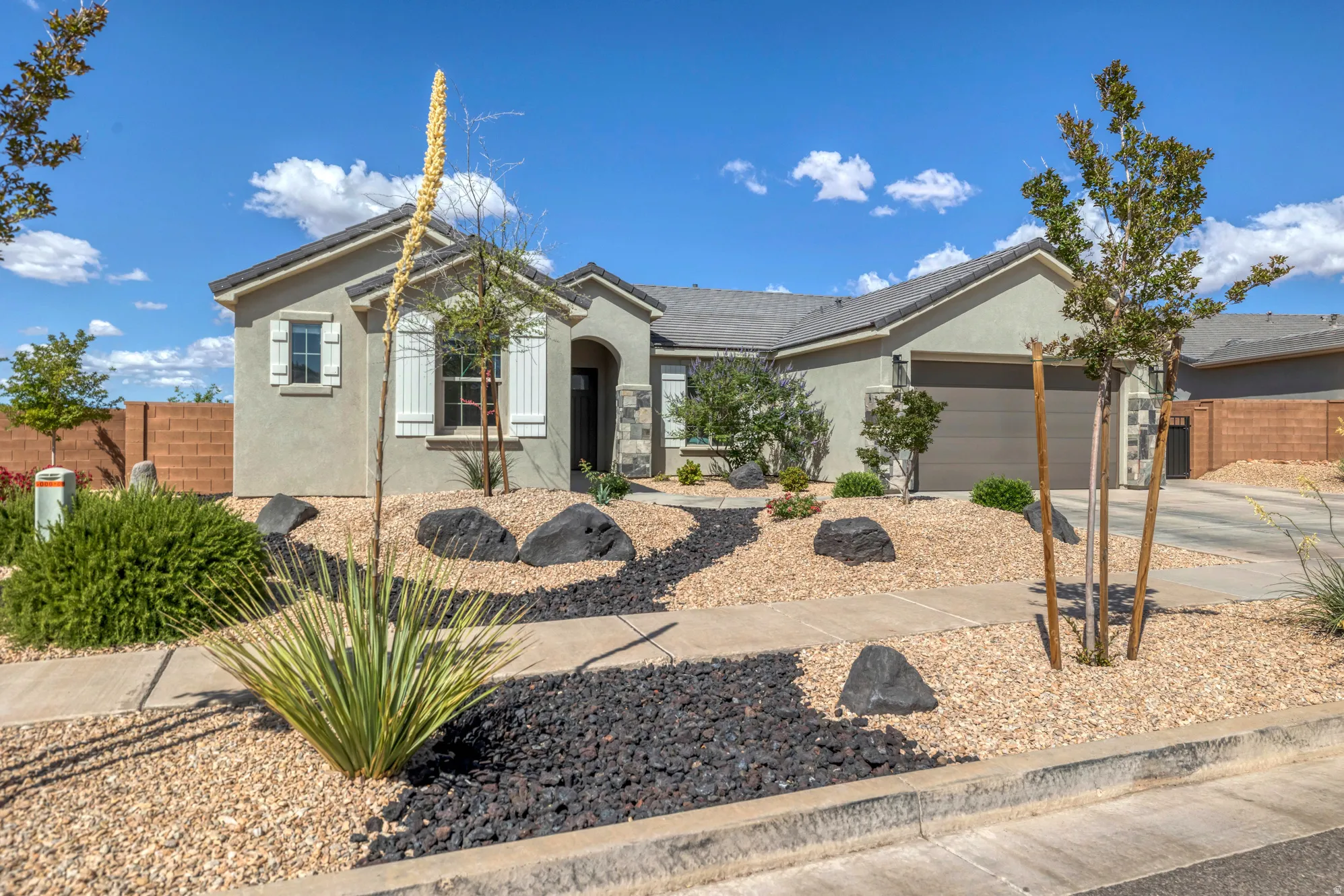 Stucco exterior featuring white louvered window shutters, an arched entry, and an attached two-car garage