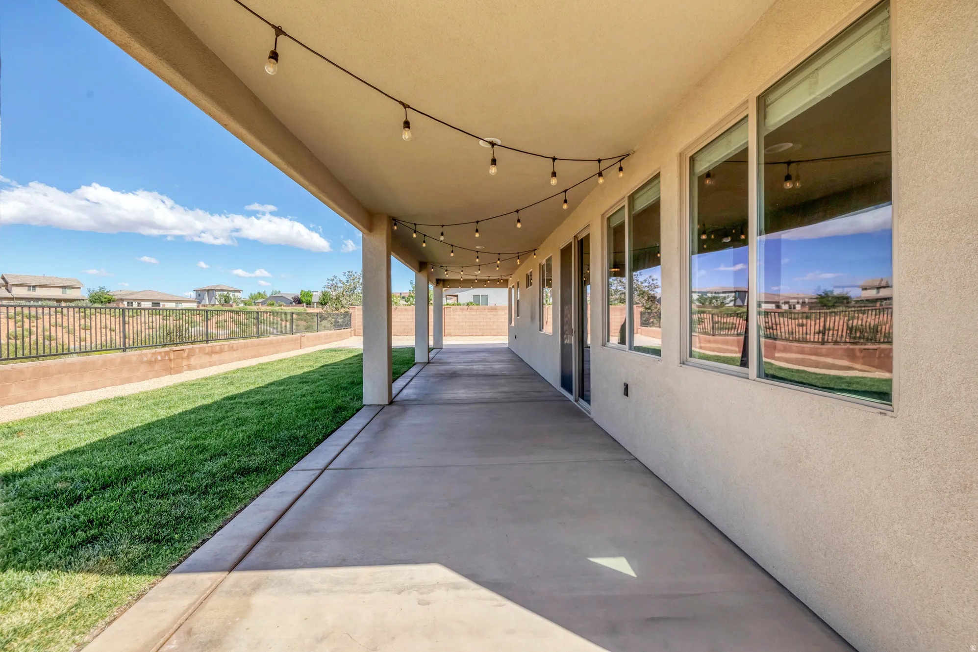 Expansive covered patio featuring string lighting and multiple columns