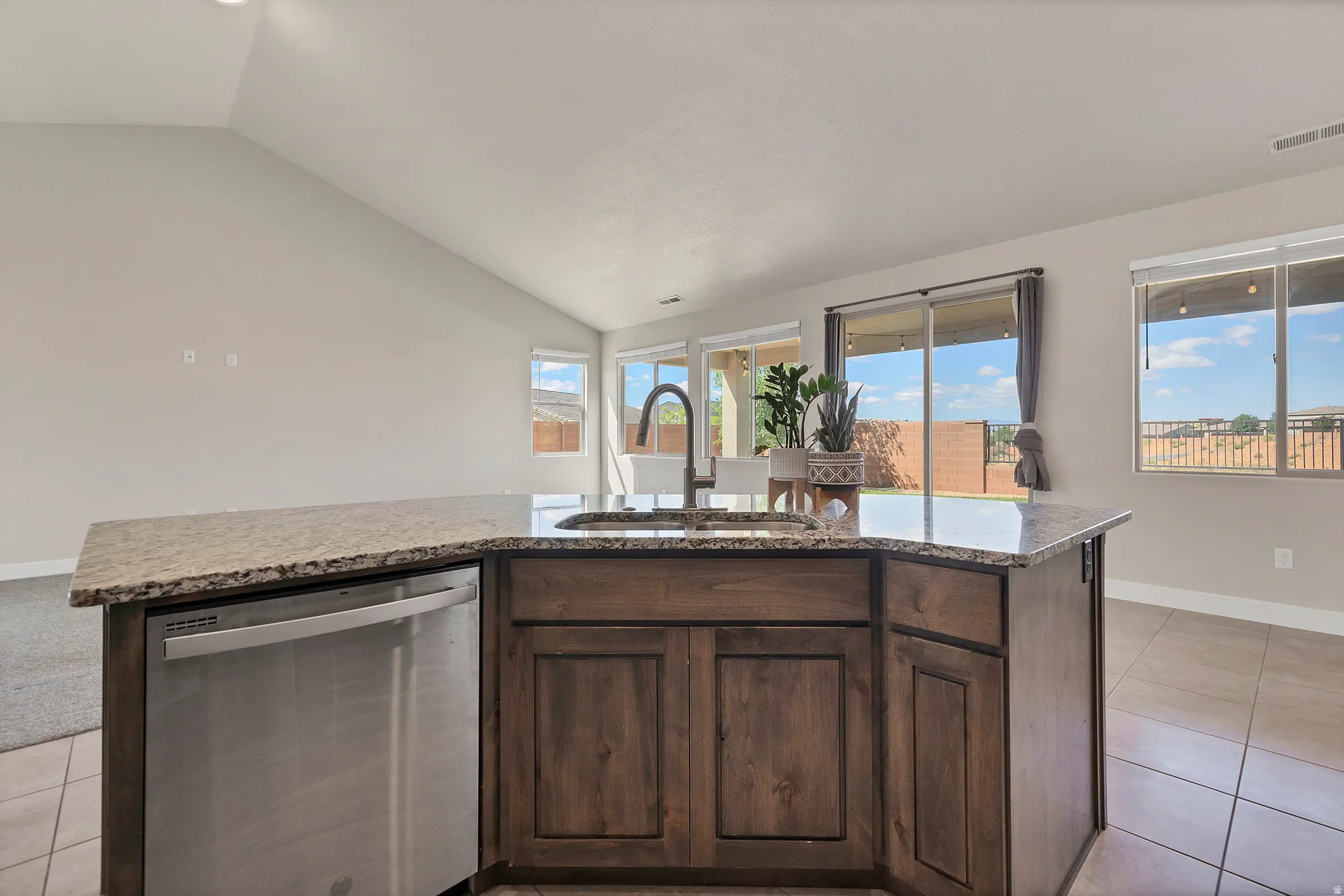 Kitchen island featuring wood-finish cabinetry, a stone-finish countertop, and a stainless steel dishwasher