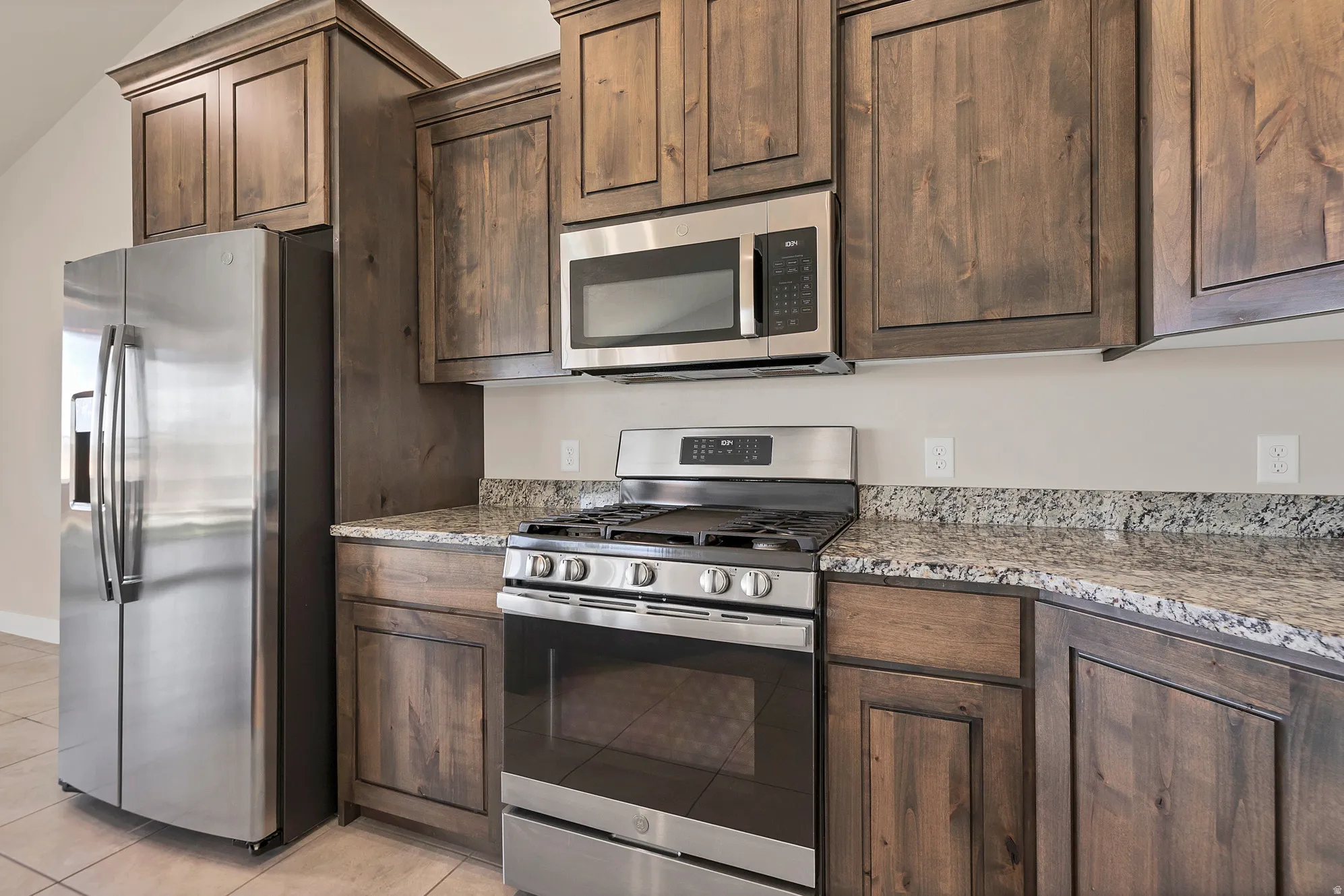 Kitchen featuring dark wood cabinetry, stainless steel appliances, and stone countertops