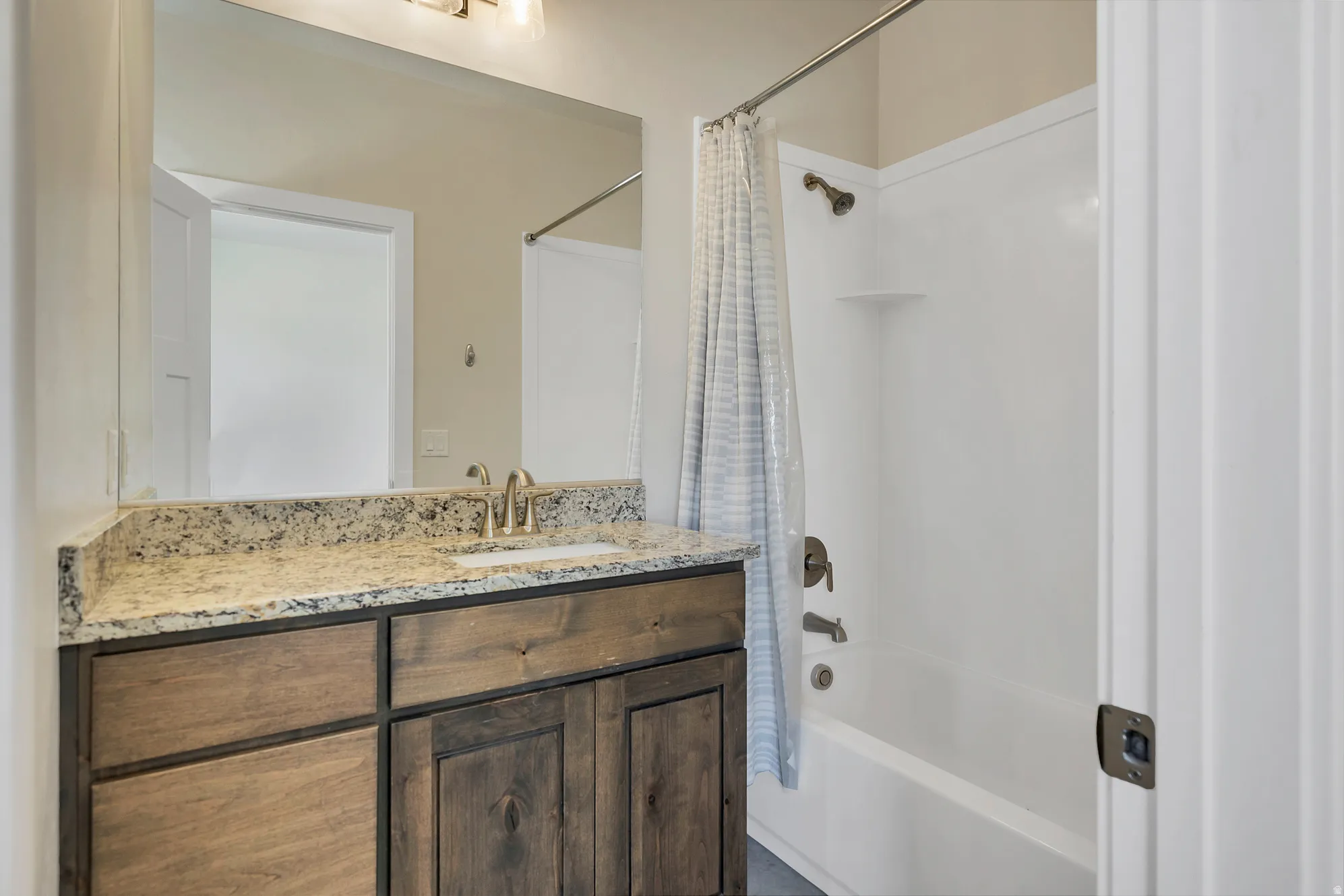 Bathroom vanity with a granite-style countertop, undermount sink, and wood-finish cabinetry