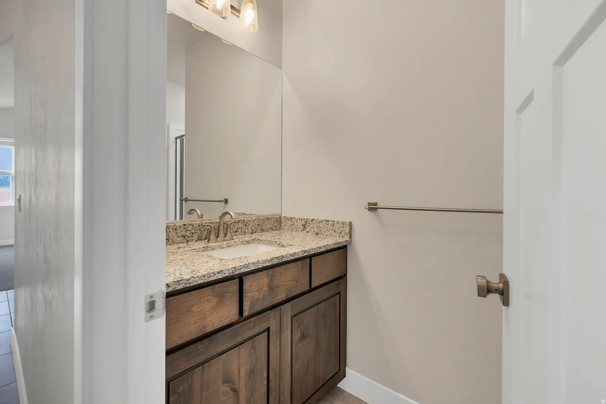 Bathroom vanity featuring a light-toned granite countertop, undermount sink, and a brushed nickel faucet