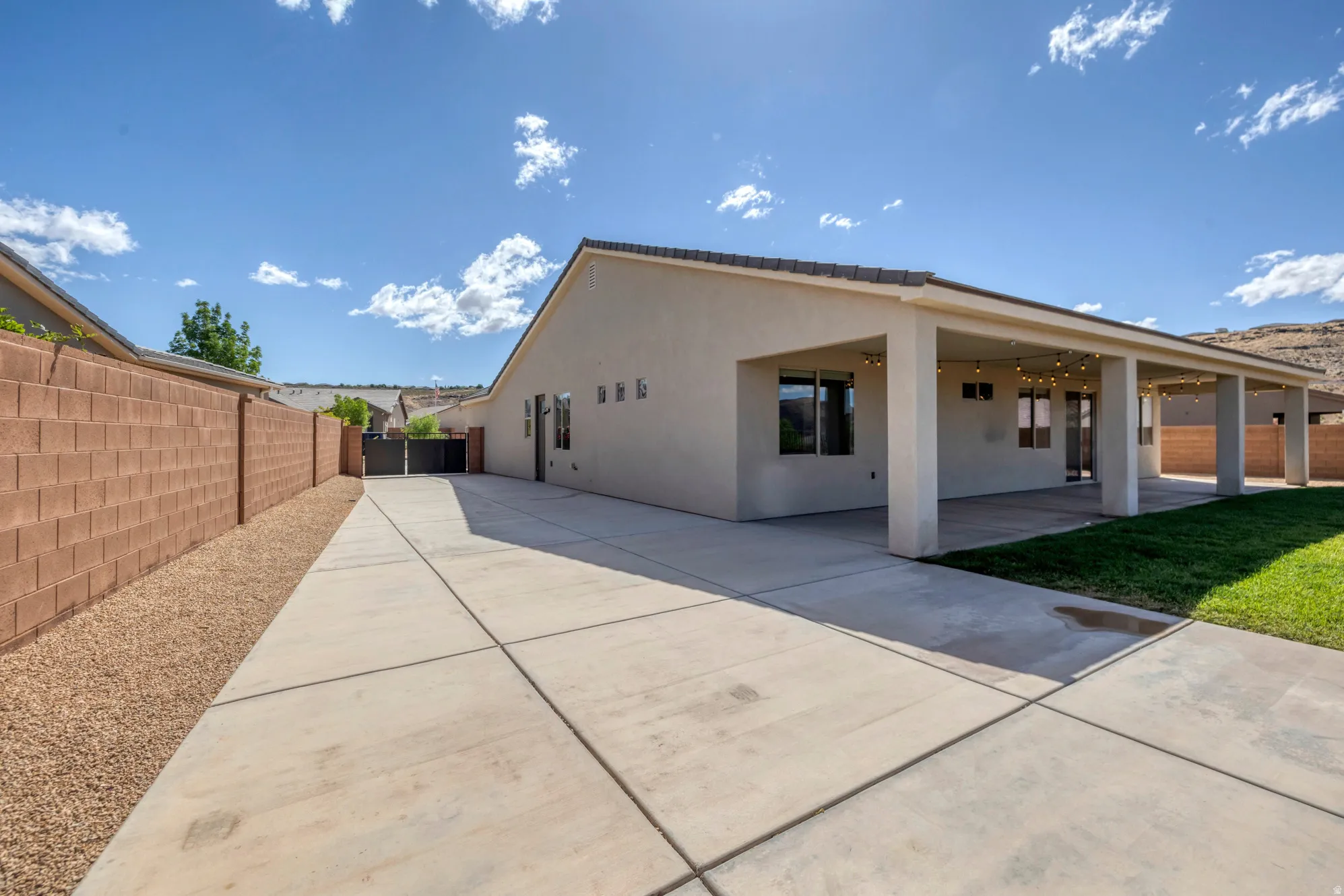 Expansive concrete driveway alongside a stucco exterior with a covered patio