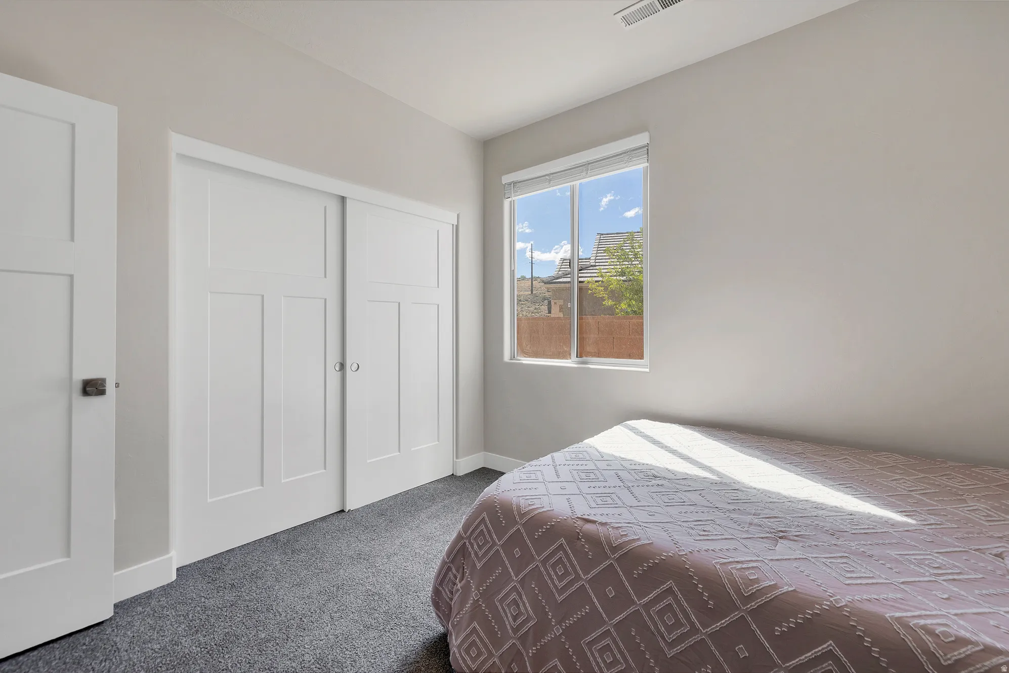 Room featuring a large window, sliding paneled closet doors, and light gray walls