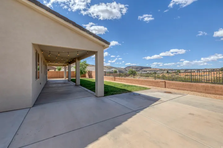Expansive covered patio featuring string lighting, stucco exterior, and a concrete surface