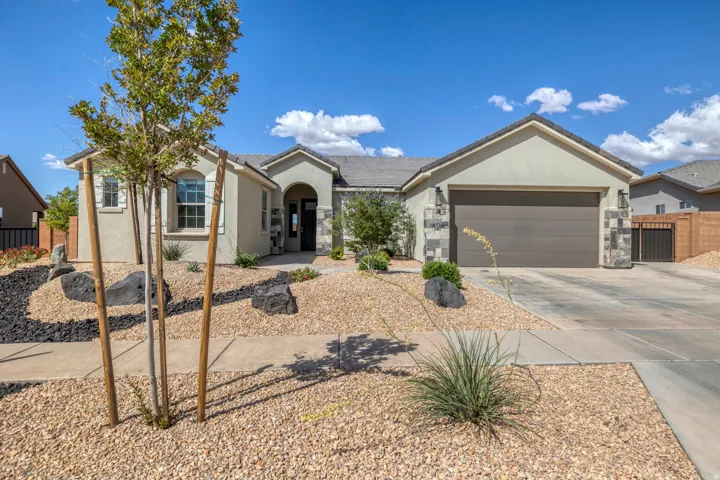 Contemporary stucco exterior with a stone veneer garage facade, a covered front entry, and a two-car garage