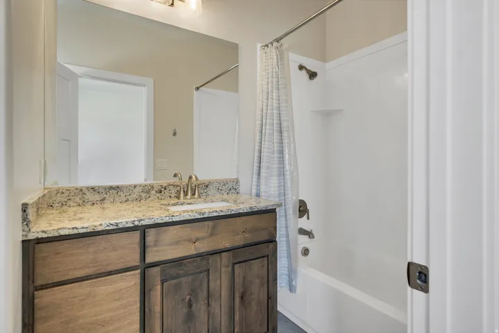Bathroom vanity with a granite-style countertop, undermount sink, and wood-finish cabinetry