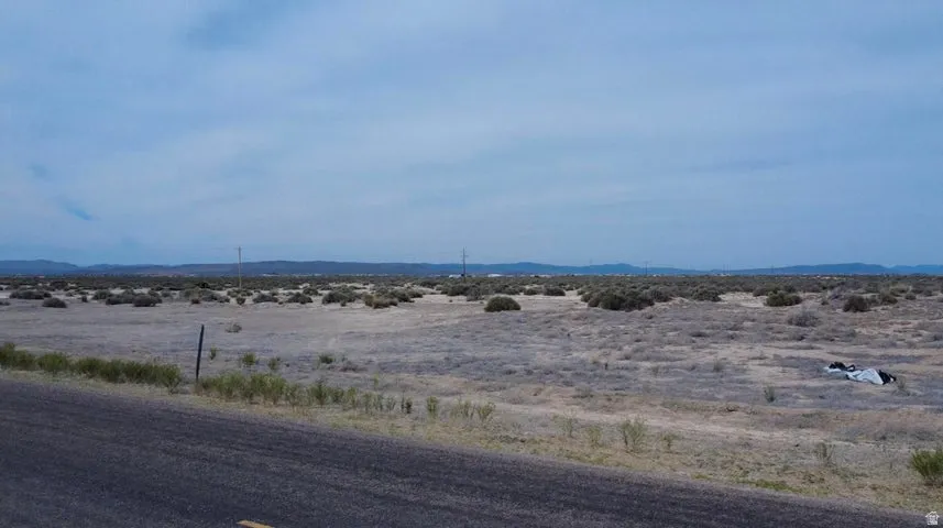 Expansive desert landscape featuring a paved road frontage and distant mountain ranges