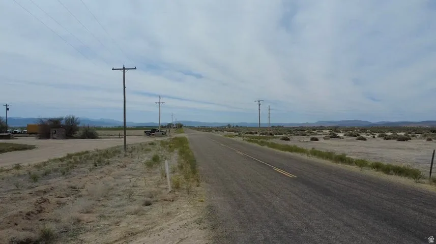 Paved road frontage with double yellow lines traversing a vast, undeveloped landscape