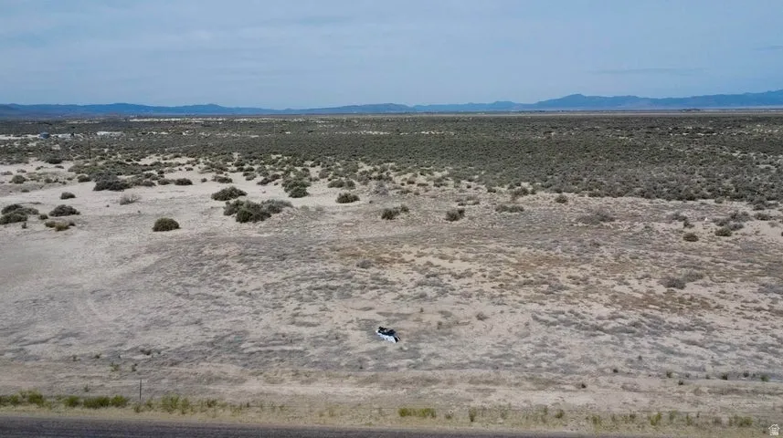 Expansive desert landscape featuring natural scrub brush and distant mountain ranges