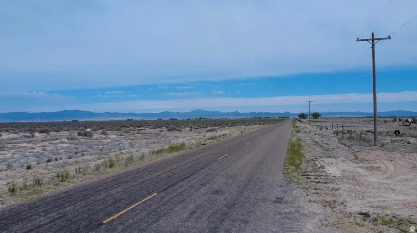 Paved road extending through a vast, arid landscape with distant mountain ranges