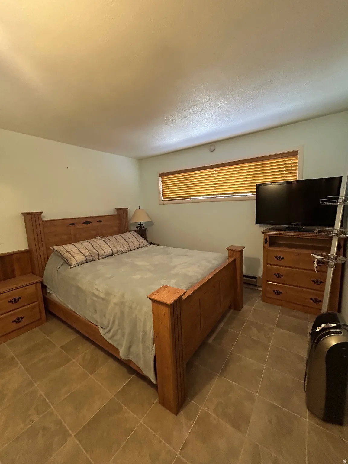 Tiled flooring extends throughout this room, featuring a horizontal window with wooden blinds and light-colored walls