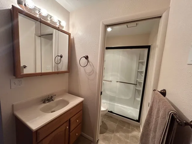 Bathroom vanity with integrated sink, wood-finish cabinetry, and a mirrored medicine cabinet