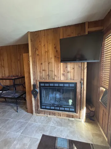Fireplace with a black metal insert and a wood-finish mantel, surrounded by vertical wood paneling