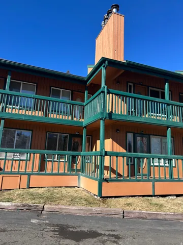 Multi-story exterior featuring vertical plank siding and green painted railings