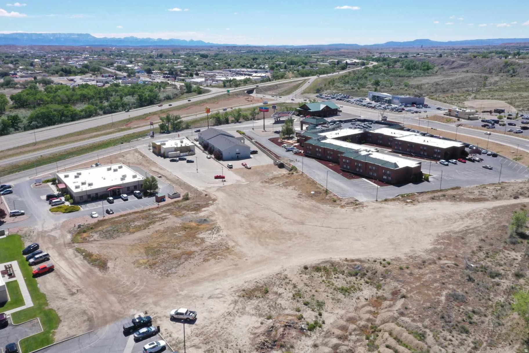 Expansive property featuring commercial buildings, substantial parking areas, and convenient access to a multi-lane highway