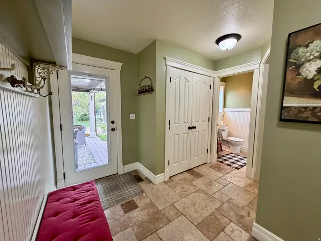 Entryway with natural stone-look tile flooring, white beadboard paneling, and a full-light exterior door
