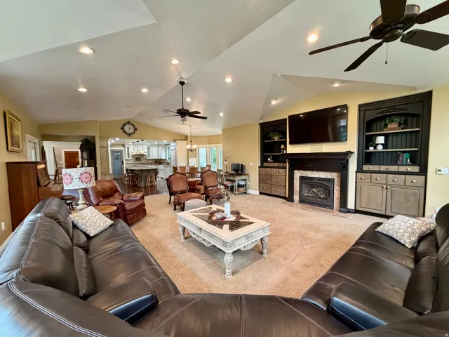Spacious living area featuring vaulted ceilings, recessed lighting, and ceiling fans